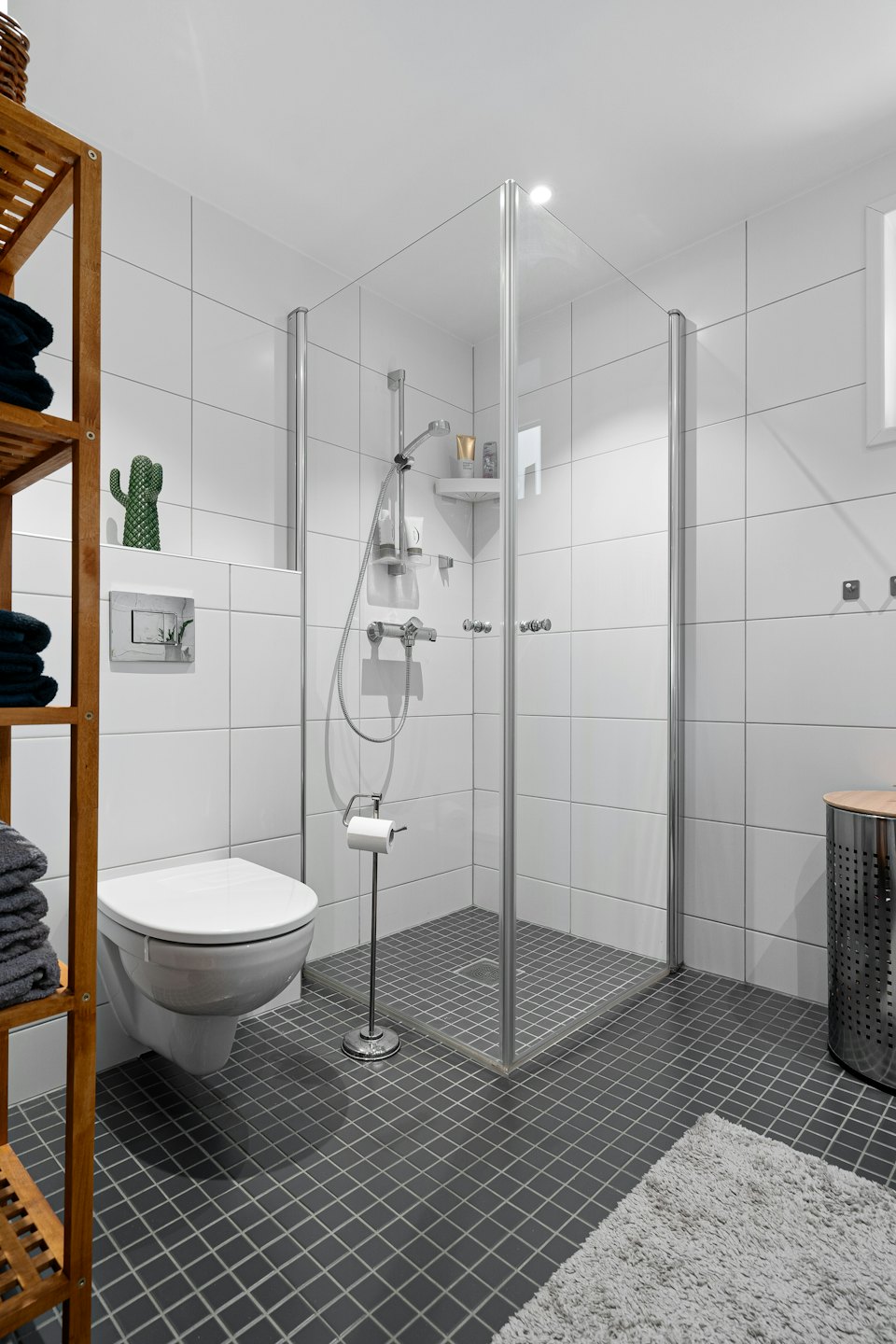 Bagno moderno con doccia e asciugamani ben impilati.